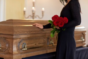woman mourning a loved one with flowers at coffin