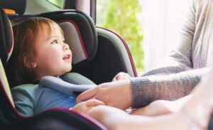 kid getting buckled into car seat
