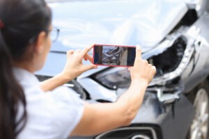 woman taking picture of car crash damage