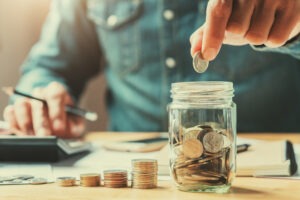 businessman-budgeting-with-jar-of-coins