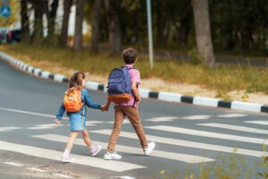 kids wearing backpacks crossing road