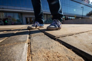 person-walking-on-broken-sidewalk