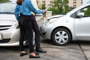two-people-surveying-car-accident-damage