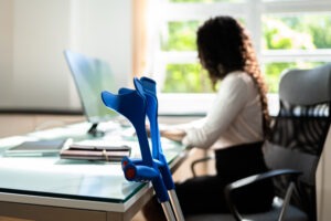 woman working with crutches next to desk